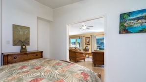 Quarto com colcha florida, cómoda de madeira e pintura na parede.