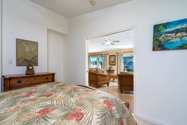 A bedroom with a floral bedspread, a wooden dresser, and a painting on the wall.