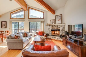 Amplia sala de estar con chimenea, ventanas grandes y televisor.