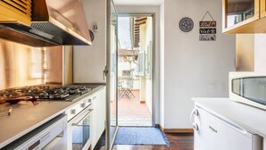 A modern kitchen with a gas stove, oven, and microwave. There is a sliding glass door leading to an outdoor patio area. - Amazing Penthouse Le Terrazze Luxury Apartment Duomo view (Firenze)