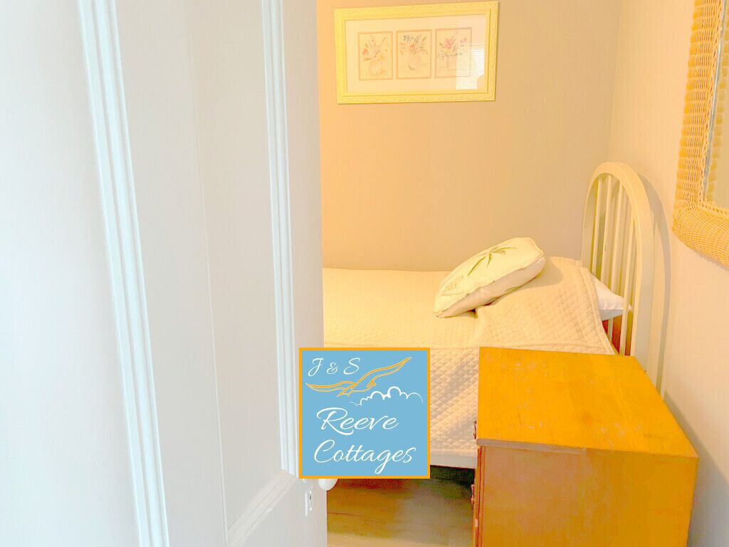 A bedroom with a bed, a bedside table, and a framed picture on the wall.