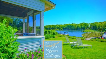 Un chalet au bord du lac, doté d’un porche couvert, d’une enseigne indiquant « J&S Reeves Cottages », et d’une pelouse verdoyante avec des chaises longues.