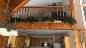 Ein Holzbalkon mit Geländer, Blumentöpfen und einem Schild mit der Aufschrift 'LIVE'.