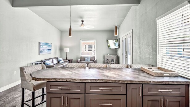 A spacious kitchen with a large island, pendant lights, and a view of the living area.