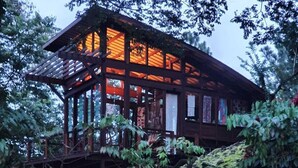 A wooden house with a glass facade, surrounded by a landscaped garden with a brick pathway. - VillaHermosa B&B (Sorá)
