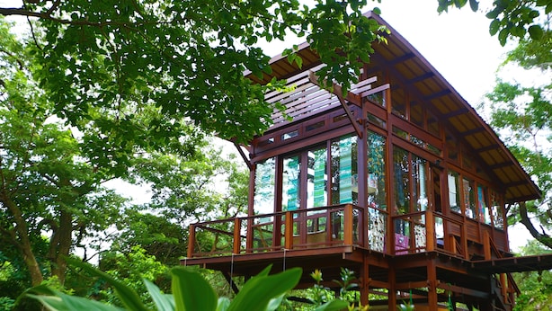 A wooden structure with multiple levels, surrounded by lush greenery and trees. - VillaHermosa B&B (Sorá)