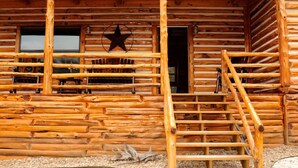 Una cabaña de madera con porche, una decoración de estrella y una escalera que lleva a la entrada.