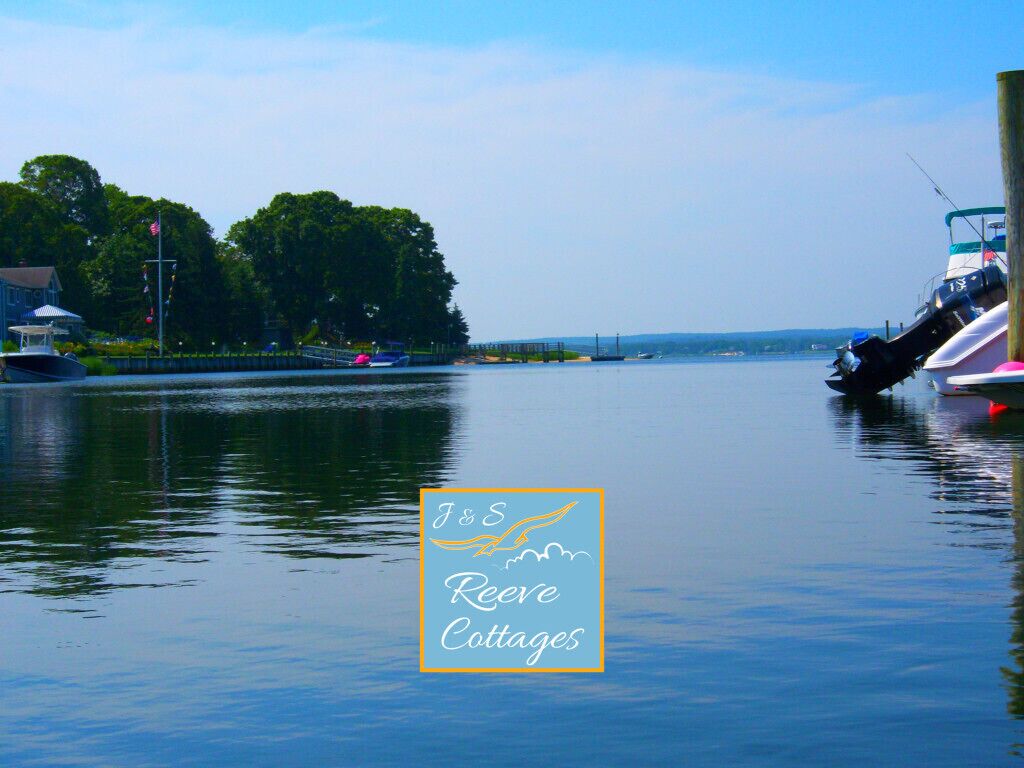 A calm water body with boats docked, a clear sky, and a logo for J&S Reeves Cottages.