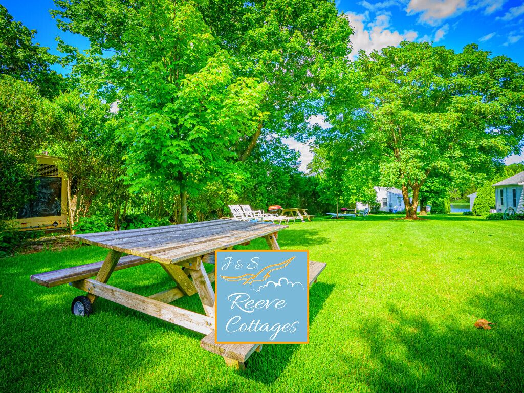 A picnic table in a grassy area with a sign for J&S Reeves Cottages.