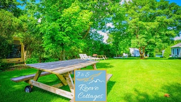 A picnic table in a grassy area with a sign for J&S Reeves Cottages.