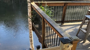 Una terraza de madera con barandilla de metal y pared de piedra.