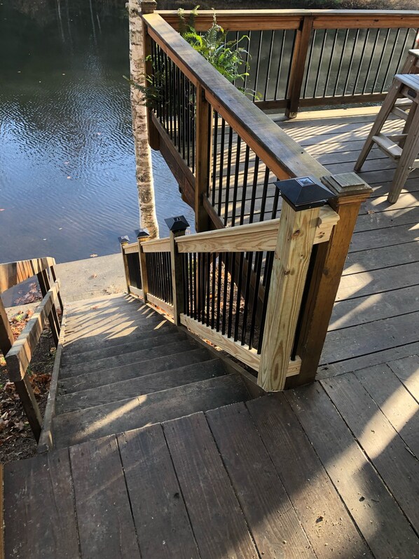 Une terrasse en bois avec une rambarde en métal et un mur en pierre.