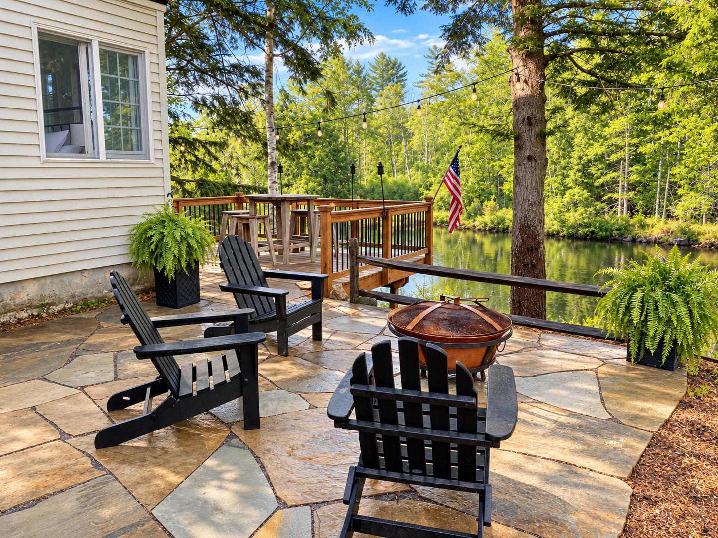 Une terrasse avec des fauteuils Adirondack, une plateforme en bois et une vue sur un lac.