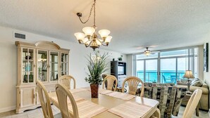 A dining area with a table, chairs, a chandelier, and a view of the ocean through large windows. - 6th Floor, Beachfront. Sundeck, Lazy River, Kiddie Pools | Bluewater Keyes - 606 (North Myrtle Beach)