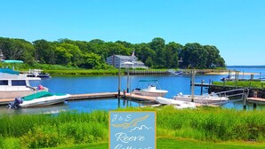 A marina with boats docked, a grassy area, and a house with a flag. - 6th of 6 Premier Waterfront Vacation Rentals on Long Island NY in Wine Country of Famed North Fork (Riverhead)