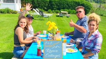 A group of people seated at an outdoor table with a blue tablecloth, enjoying a meal.