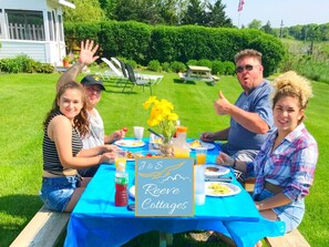 A group of people seated at an outdoor table with a blue tablecloth, enjoying a meal.