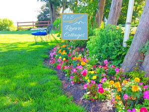 A garden with a sign for J&S Reeves Cottages, surrounded by colorful flowers and a wooden fence.