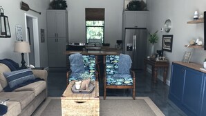 A compact living space with a kitchenette, two patterned chairs, a sofa, and a small table.