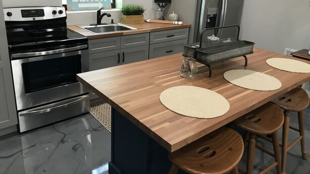 A modern kitchen with a wooden island, stainless steel appliances, and a sign reading "BEACH".