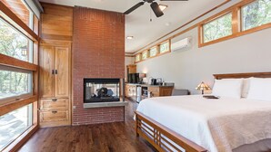 A bedroom with a large bed, wooden headboard, a fireplace, and a ceiling fan.