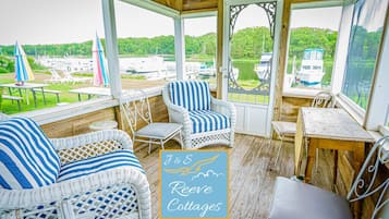 Un espace extérieur aménagé, abrité et doté de mobilier en osier, offrant une vue sur les bateaux sur un lac.