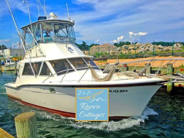A white boat with 'BLACK ROCK' written on the side, docked at a marina with a clear sky and rocky landscape in the background. - 3rd of 6 Premier Waterfront Vacation Rentals on Long Island NY in Wine Country of Famed North Fork (Aquebogue)