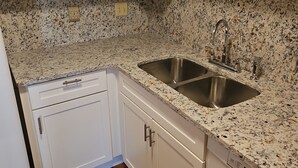 A kitchen with white cabinets, a granite countertop, and a stainless steel sink.