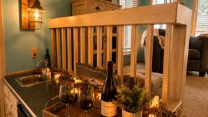Een keuken met een houten aanrecht, wijnglazen, een fles wijn en een kaars.