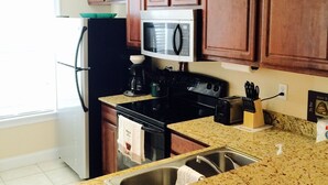Una cocina con gabinetes de madera, microondas, estufa y lavabo.