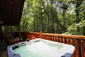 Un jacuzzi en una terraza de madera con vistas a un bosque.