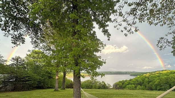 A hammock tied to a tree in a grassy area with a lake and a rainbow in the background. - Rustic Charm Cabin for Families, Couples, or Fishing, Hunting  ON Norfork Lake!  (Gamaliel)