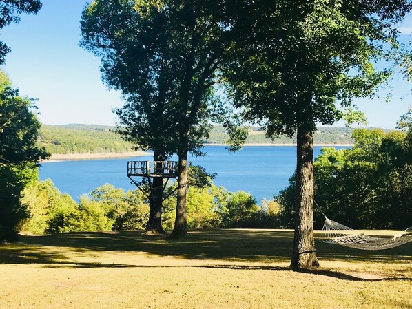 A hammock and a treehouse overlooking a lake.