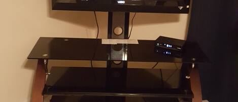 A television on a black stand with a cable box below it.