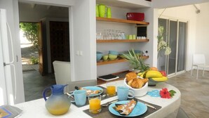 A breakfast setup with a table, breakfast items, and a view of the outdoor area.