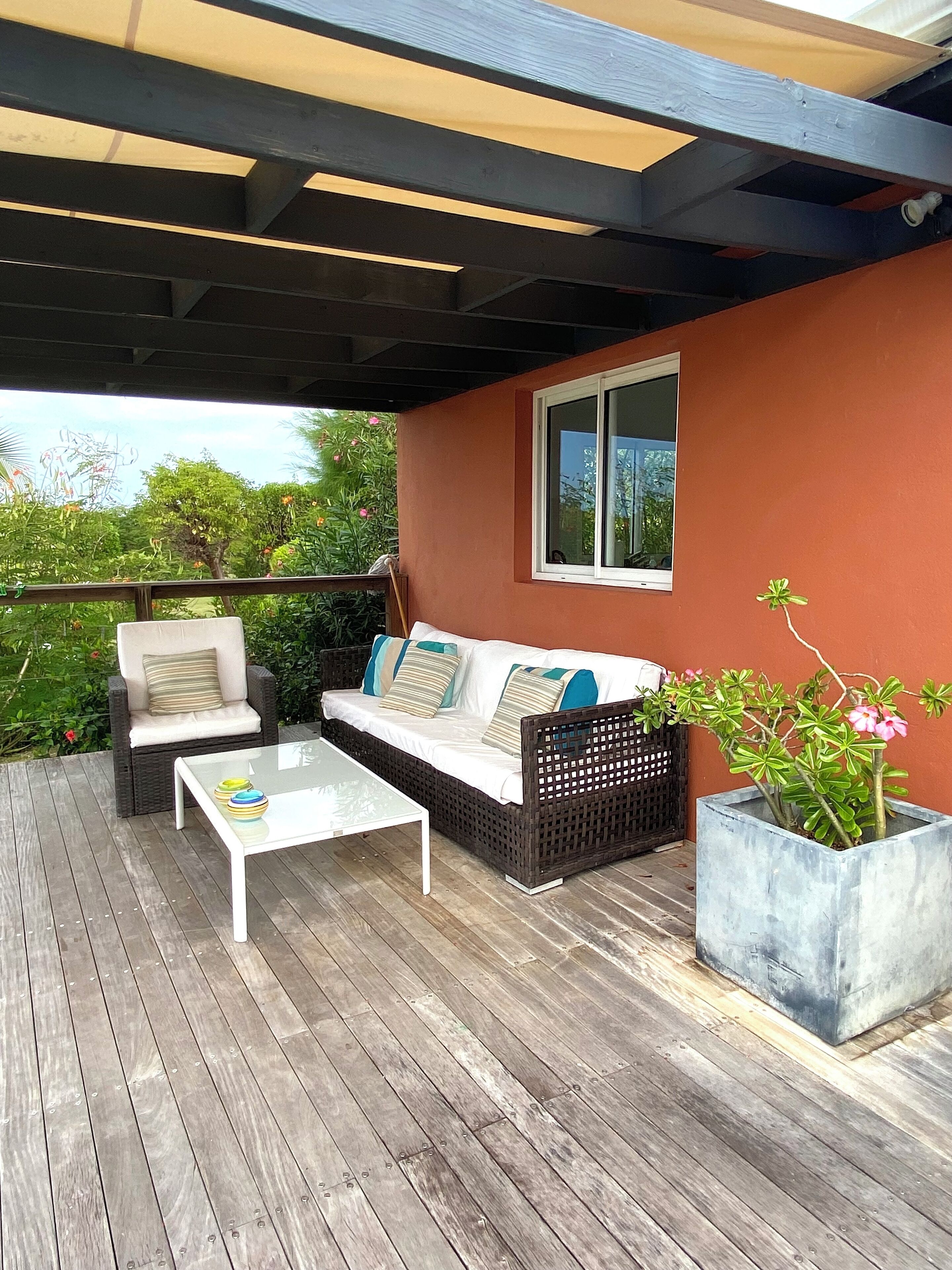 A covered outdoor seating area with a sofa, chairs, and a table.
