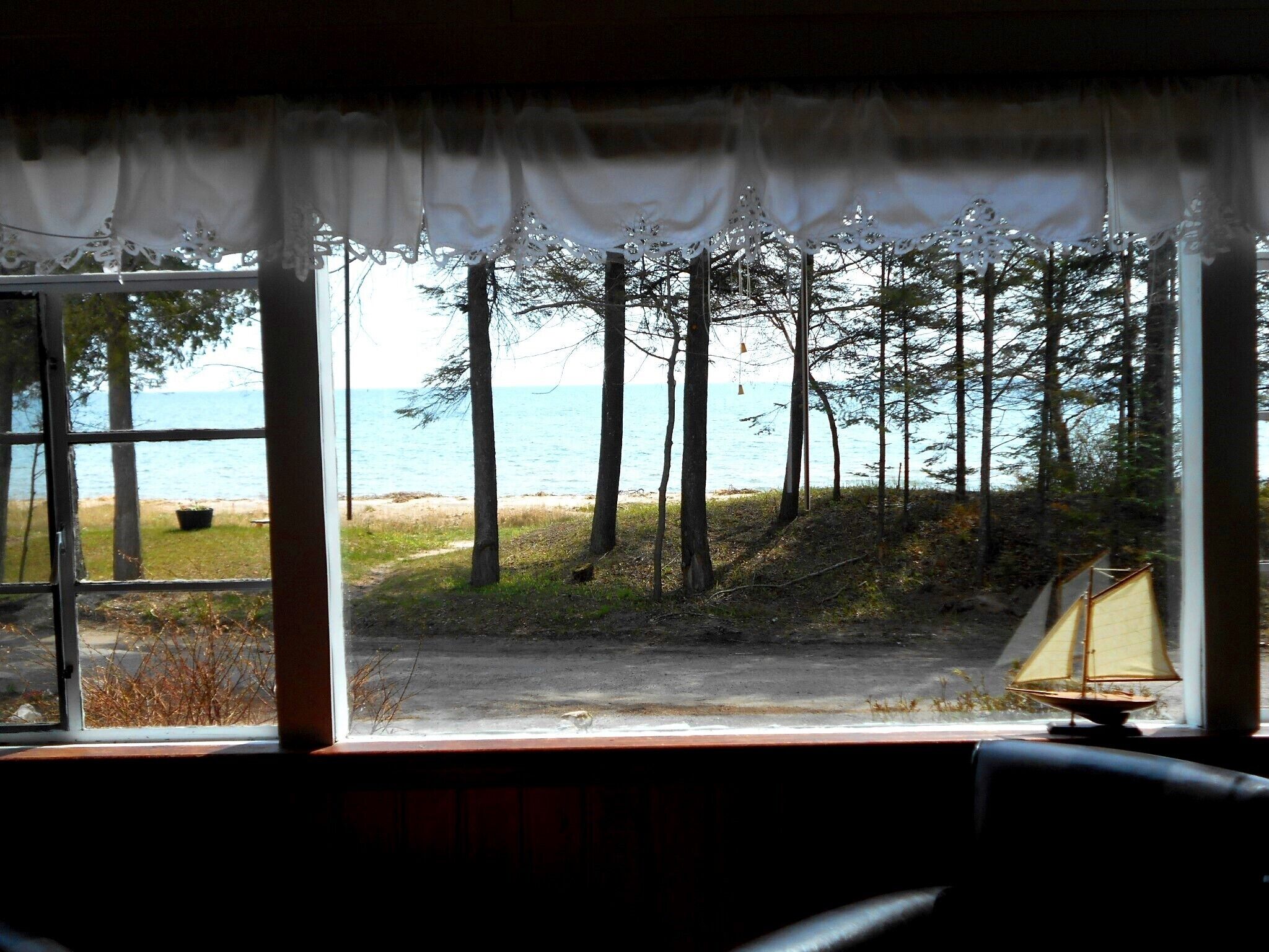 Une pièce avec vue sur la mer, donnant sur celle-ci par une fenêtre ornée de rideaux en dentelle.