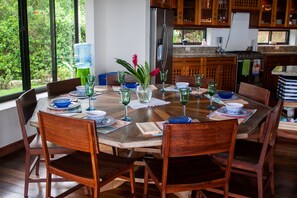 A dining area with a wooden table set for six, surrounded by wooden chairs.