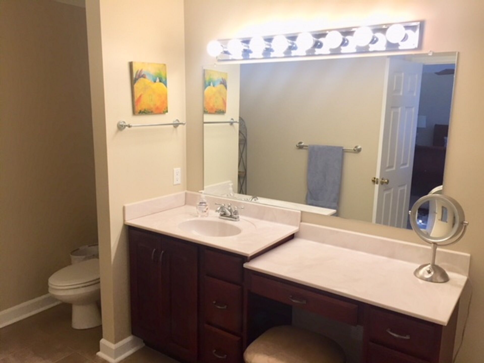 Une salle de bain avec un meuble-lavabo à deux vasques, un grand miroir et un porte-serviettes.