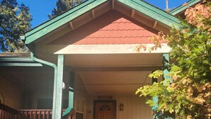 A wooden staircase leading to a porch with a green roof and a door labeled 'Guestroom.'
