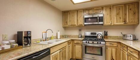A kitchen with wooden cabinets, a dishwasher, a stove, a microwave, and a toaster.