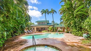 A pool area with a hot tub, lounge chairs, and a house in the background. - Stunning Gated Home, Private Pool & Spa (Lahaina)