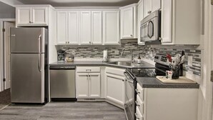 Una cocina moderna con armarios blancos, electrodomésticos de acero inoxidable y un salpicadero de azulejos.