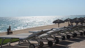 A beachside view with sun loungers, umbrellas, and a wheelchair on the sand. - In The Middle Of All, Ocean Front Ground Floor 2BD. Steps from the beach Phase 1 (Puerto penasco)