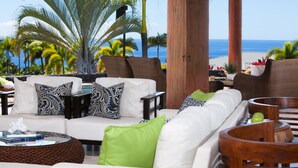 A modern living room with a white sofa, patterned cushions, and a view of the ocean. - Ocean View Home (Kailua-Kona)