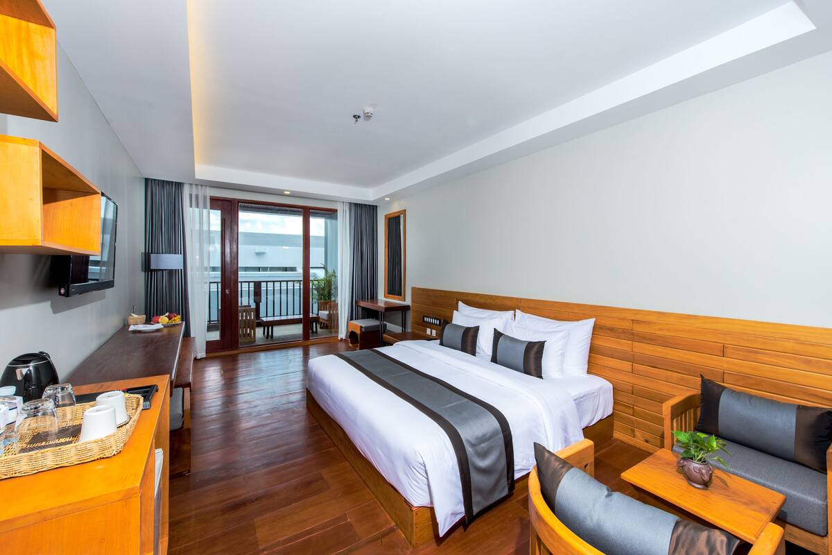 A hotel room with a large bed, wooden furniture, a desk with a lamp, and a view of the outdoors.