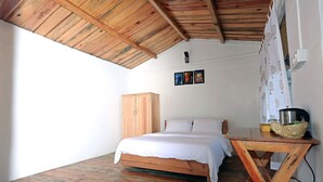 A bedroom with a wooden ceiling, a bed, a wooden wardrobe, and a table with a kettle. - Banlekhi (Dhari)