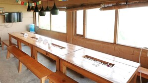 A long wooden table with multiple benches, a water cooler, and a television mounted on the wall. - Banlekhi (Dhari)