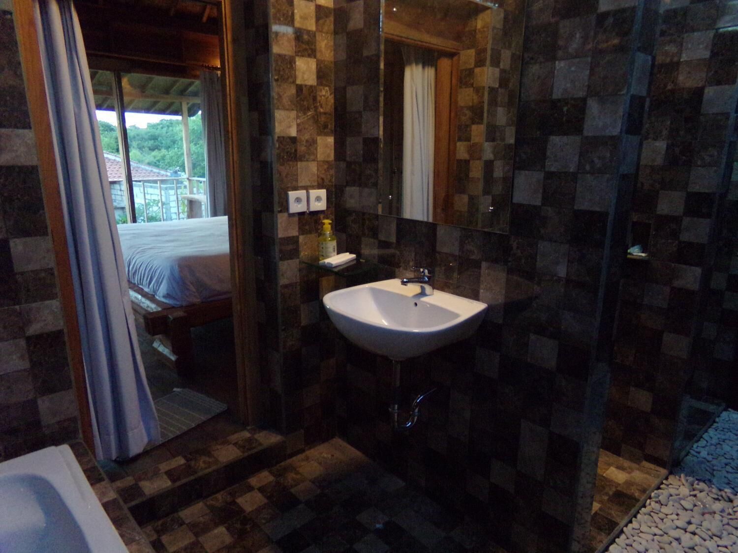 A bathroom with a white sink, a mirror, and a checkered floor.