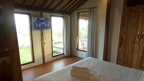 Een slaapkamer met een groot bed, een televisie en uitzicht op de omgeving via een schuifdeur.